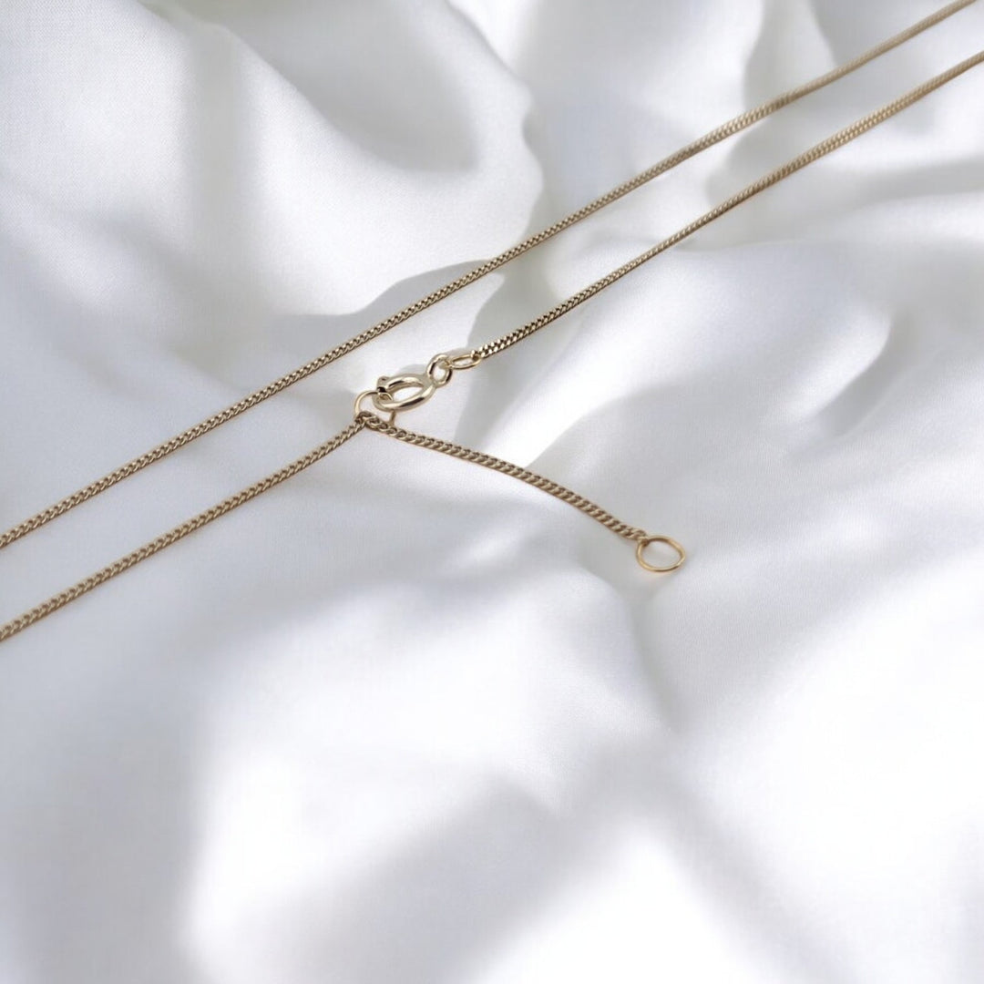 Minimalist silver necklace from RossJewelrys with two clasp options – styled on soft white fabric.

