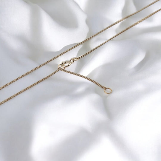 Minimalist silver necklace from RossJewelrys with two clasp options – styled on soft white fabric.

