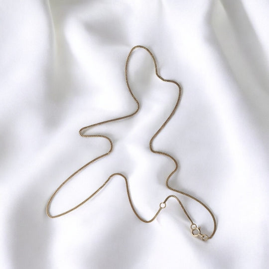 Close-up of 925 silver box chain necklace on white fabric with spring ring clasp – elegant minimalist jewelry by RossJewelrys.

