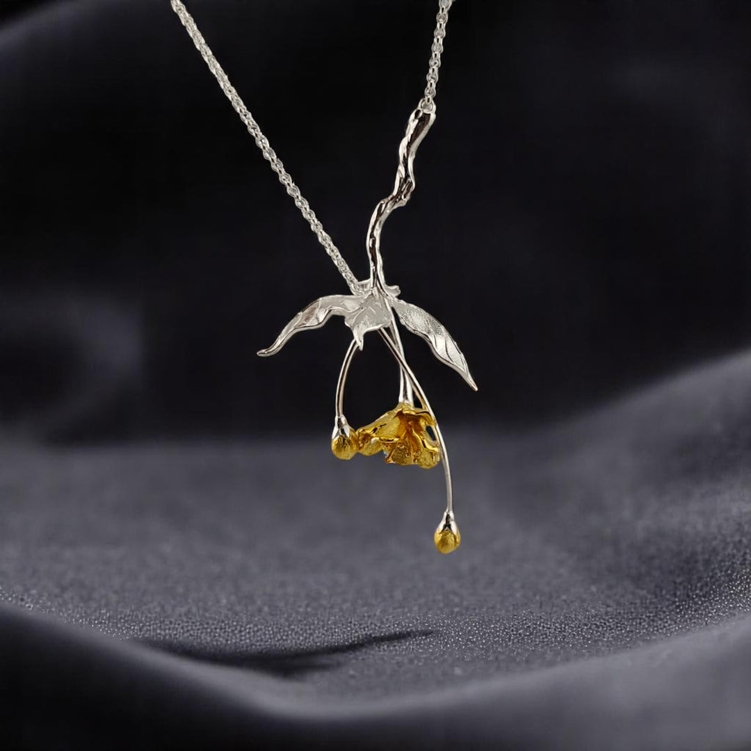 Close-up of a white-gold floral necklace with golden flower accents on soft fabric background

