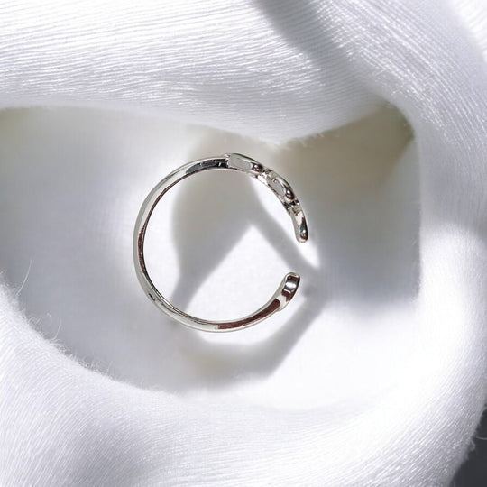 Top view of open silver ring resting on soft white cloth