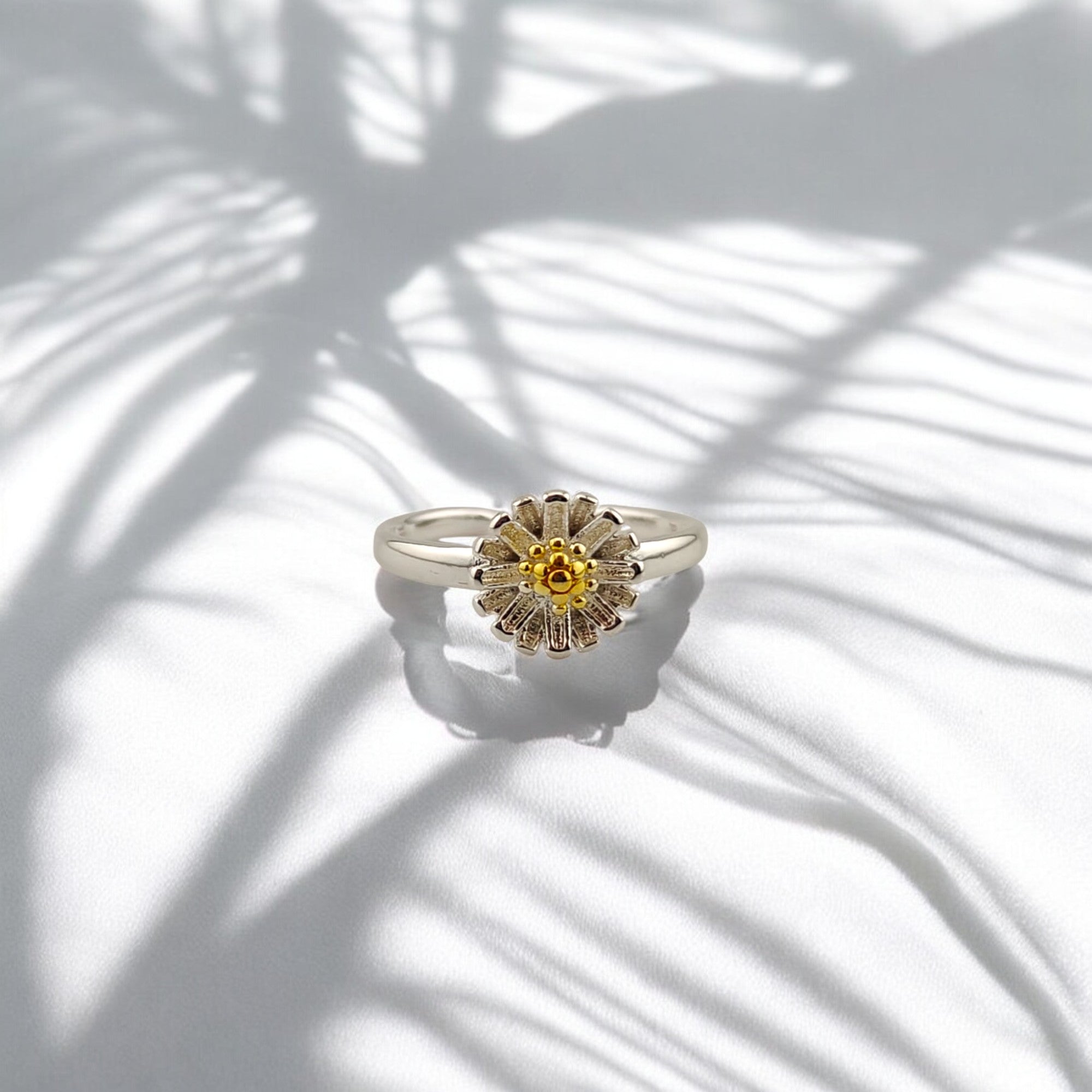 Front-facing sunflower ring with reflective petals and golden core on soft lighting