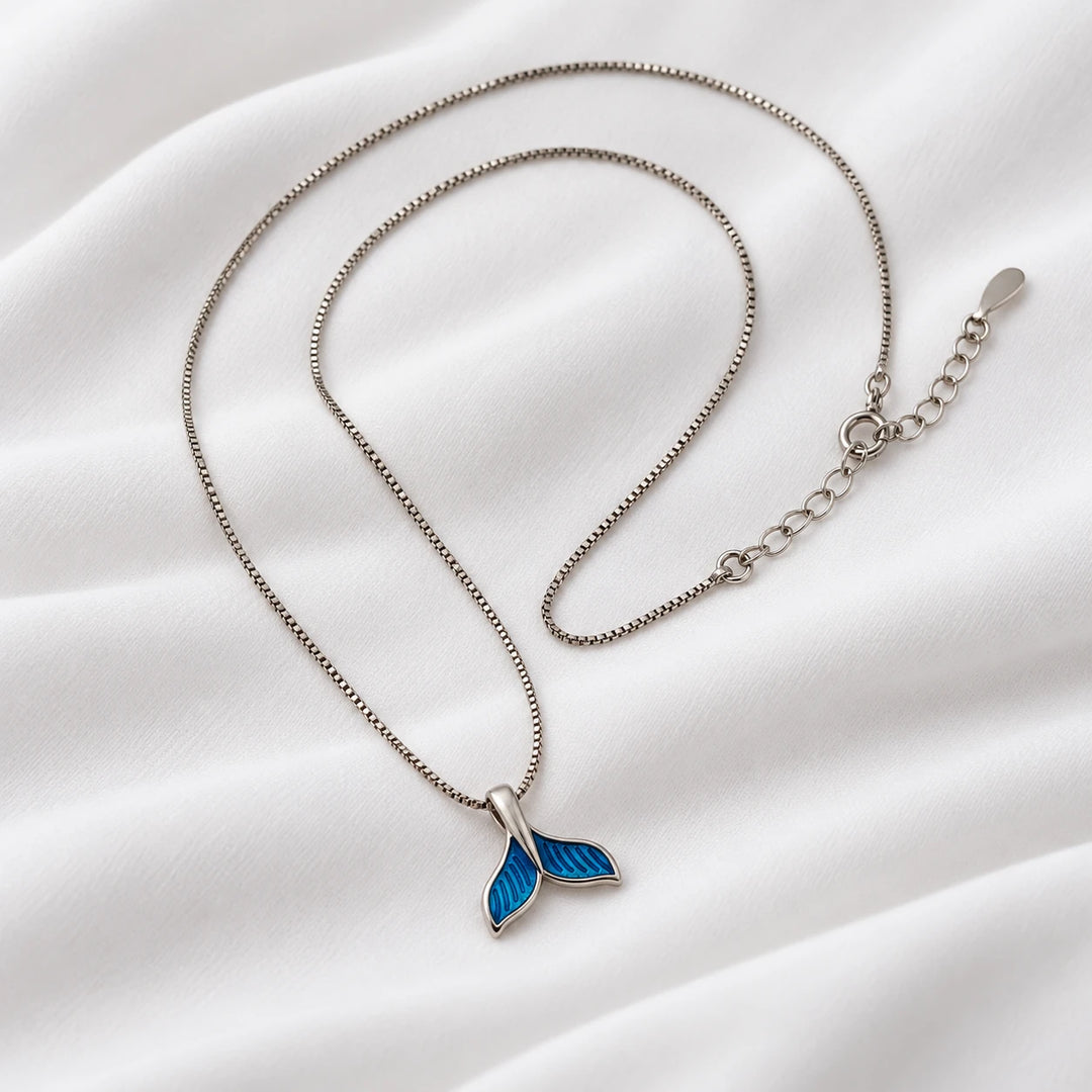 Angled view of the blue dolphin tail pendant and silver-tone necklace chain