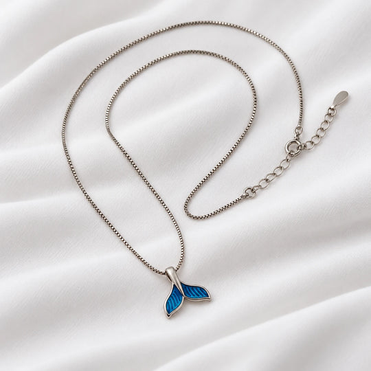 Angled view of the blue dolphin tail pendant and silver-tone necklace chain