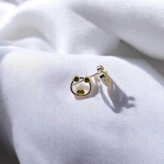 Angled view of the two-tone pig stud earrings with butterfly backs