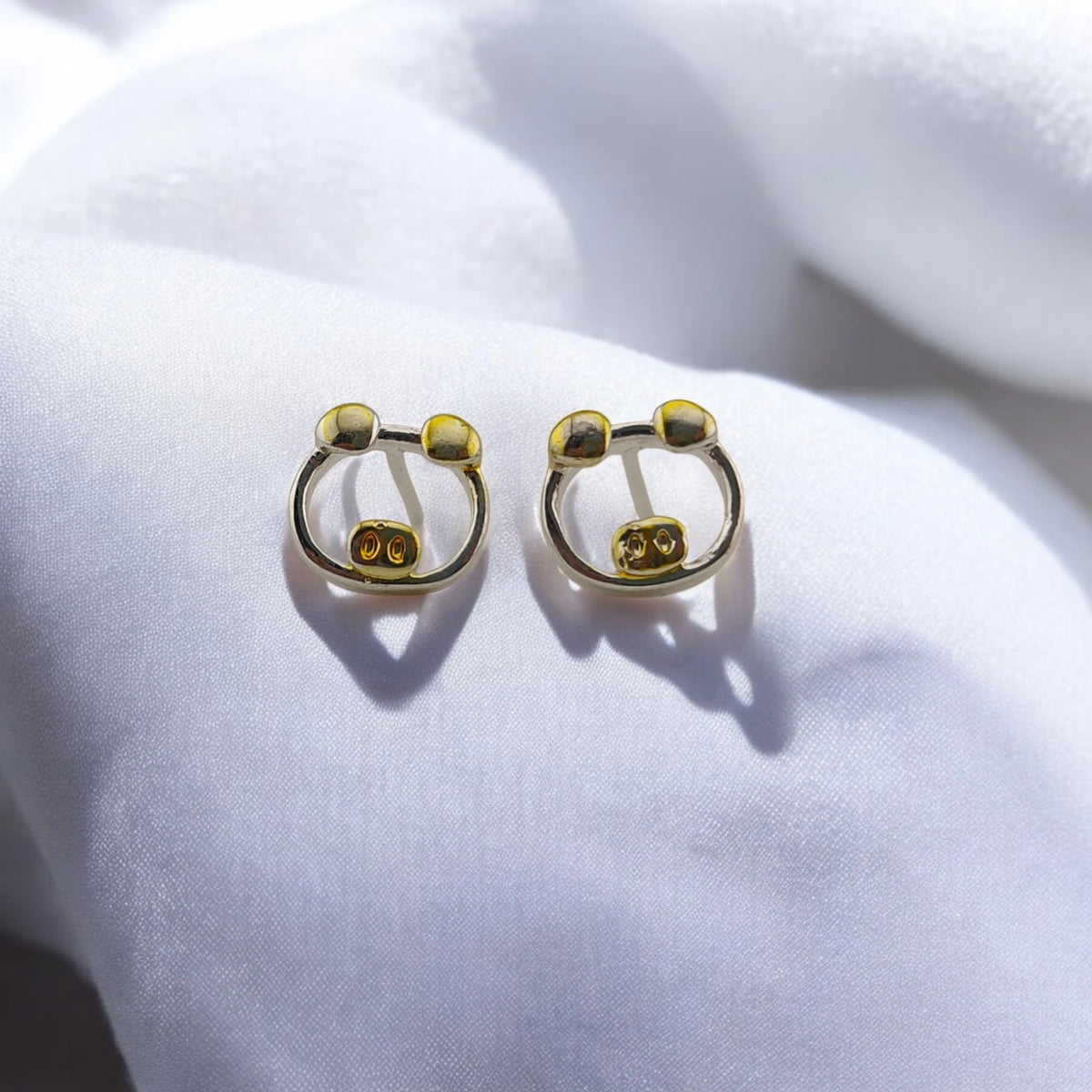 Pair of pig stud earrings with silver-tone outlines and gold-tone ears and noses