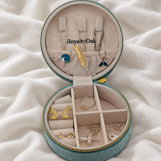 Teal travel jewelry case with necklaces on lid hooks and jewelry in the lower compartments