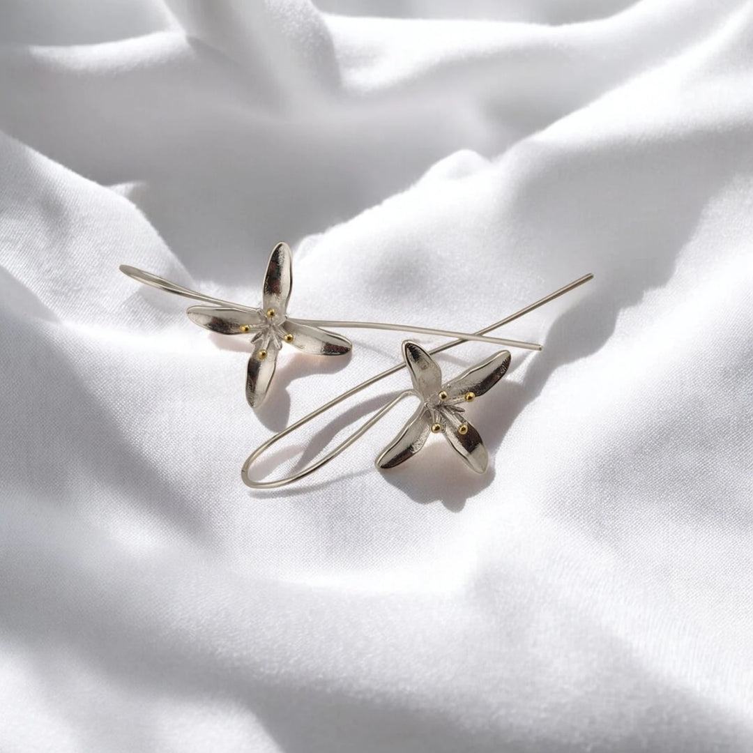 Angled view of trumpet flower earrings with long curved ear wires