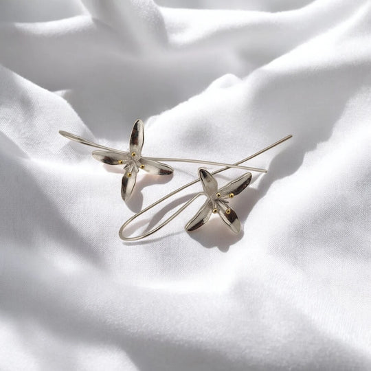 Angled view of trumpet flower earrings with long curved ear wires
