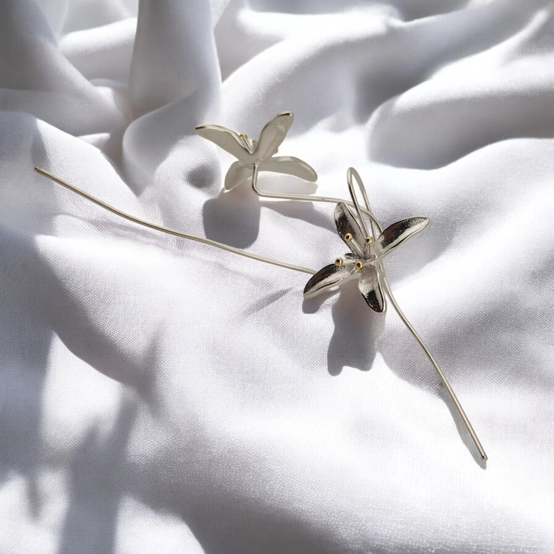 Detailed view of two trumpet flower earrings and their curved ear wires