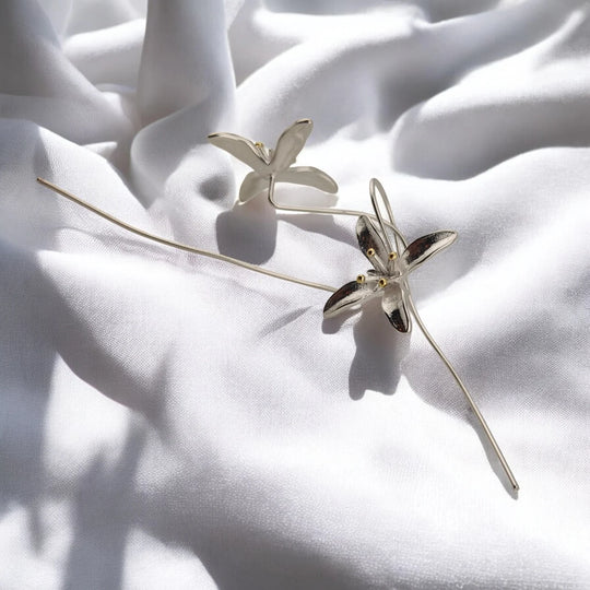 Detailed view of two trumpet flower earrings and their curved ear wires