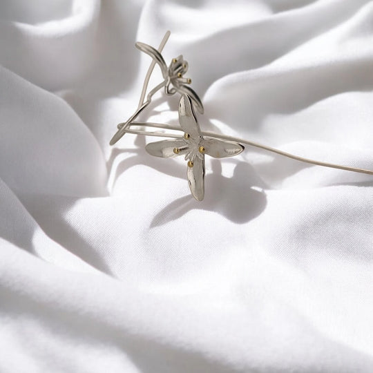 Close-up of trumpet flower earring petals and small gold-tone center details